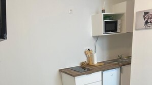 Une cuisine moderne avec des meubles blancs, un four à micro-ondes et un évier. On y trouve une table à manger avec des assiettes, des verres et des couverts.