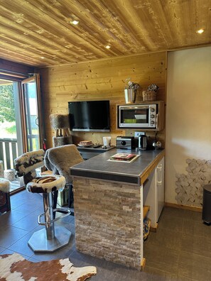 A modern kitchen with a stone countertop, wooden ceiling, and a television. - Luxury Burberry (Demi-Quartier)