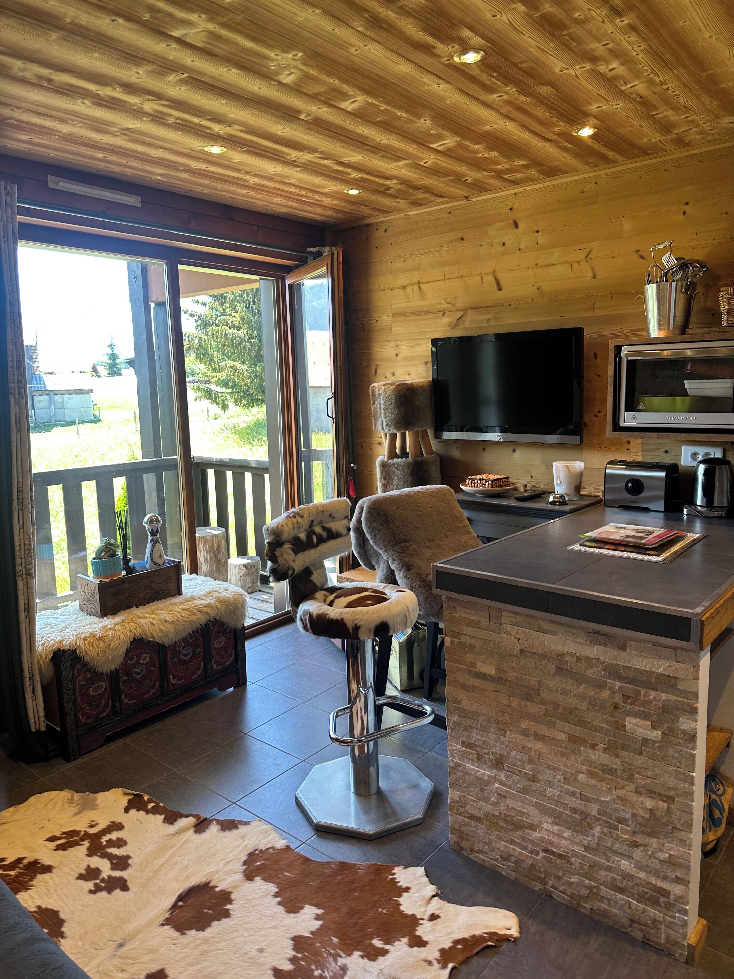 Ein Holzinterieur mit Barbereich, einem Fernseher und einem großen Fenster.