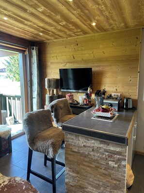 A cozy kitchen with a stone island, wooden ceiling, and a flat-screen TV. - Luxury Burberry (Demi-Quartier)