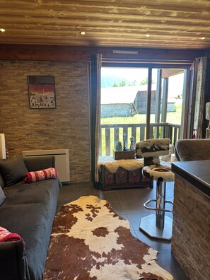 A cozy living room with a sofa, a cowhide rug, a wooden ceiling, and a view of the outdoors. - Luxury Burberry (Demi-Quartier)