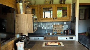 A modern kitchen with wooden cabinets, a central island, and a dining area with a sofa. - Luxury Burberry (Demi-Quartier)
