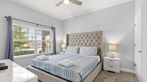 A bedroom with a bed, bedside tables, a ceiling fan, and a window with blinds. - Enchanting 4BR Villa / Family Vacation Home Near Disney (Kissimmee)