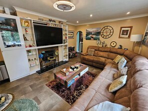 A living room with a sofa, a TV, a fireplace, and various decorative items.