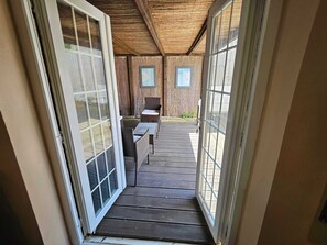 A wooden deck with outdoor furniture, a sliding glass door, and a view of the surrounding area.