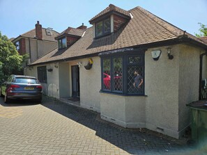 A two-story house with a tiled roof, a front door, and a window with a metal grill.