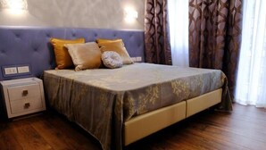 A bedroom with a bed, a nightstand, and a wall-mounted light fixture. - St Peter SUITES WINTER (Roma)