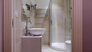 A modern bathroom with a white sink, mirror, and glass shower enclosure. - St Peter SUITES WINTER (Roma)