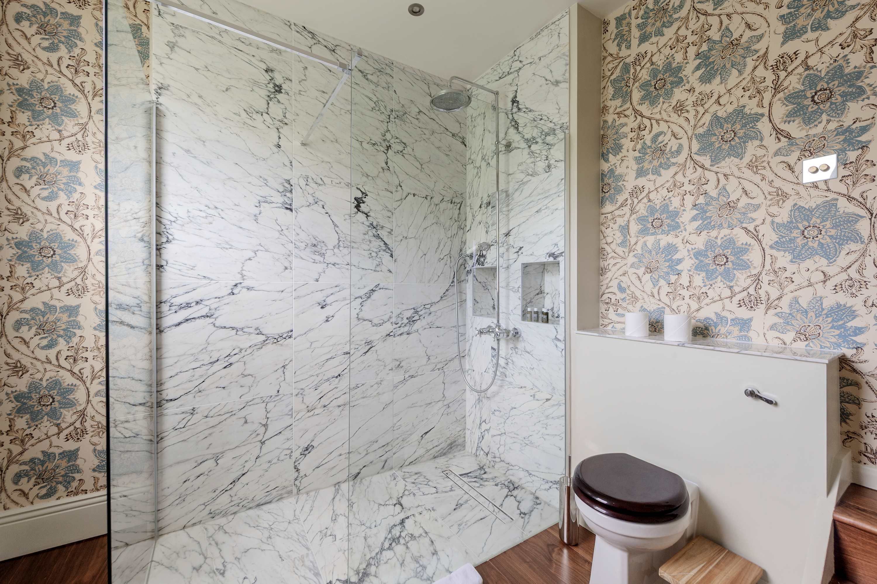 A bathroom with a glass-enclosed shower, a toilet, and a sink.
