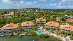 Um resort com vários edifícios, piscina e barcos atracados perto da água.