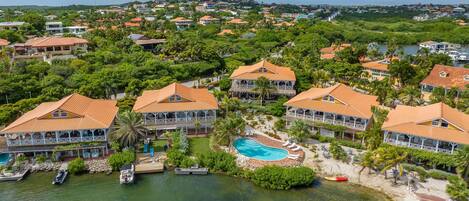 A resort with multiple buildings, a swimming pool, and boats docked near the water.