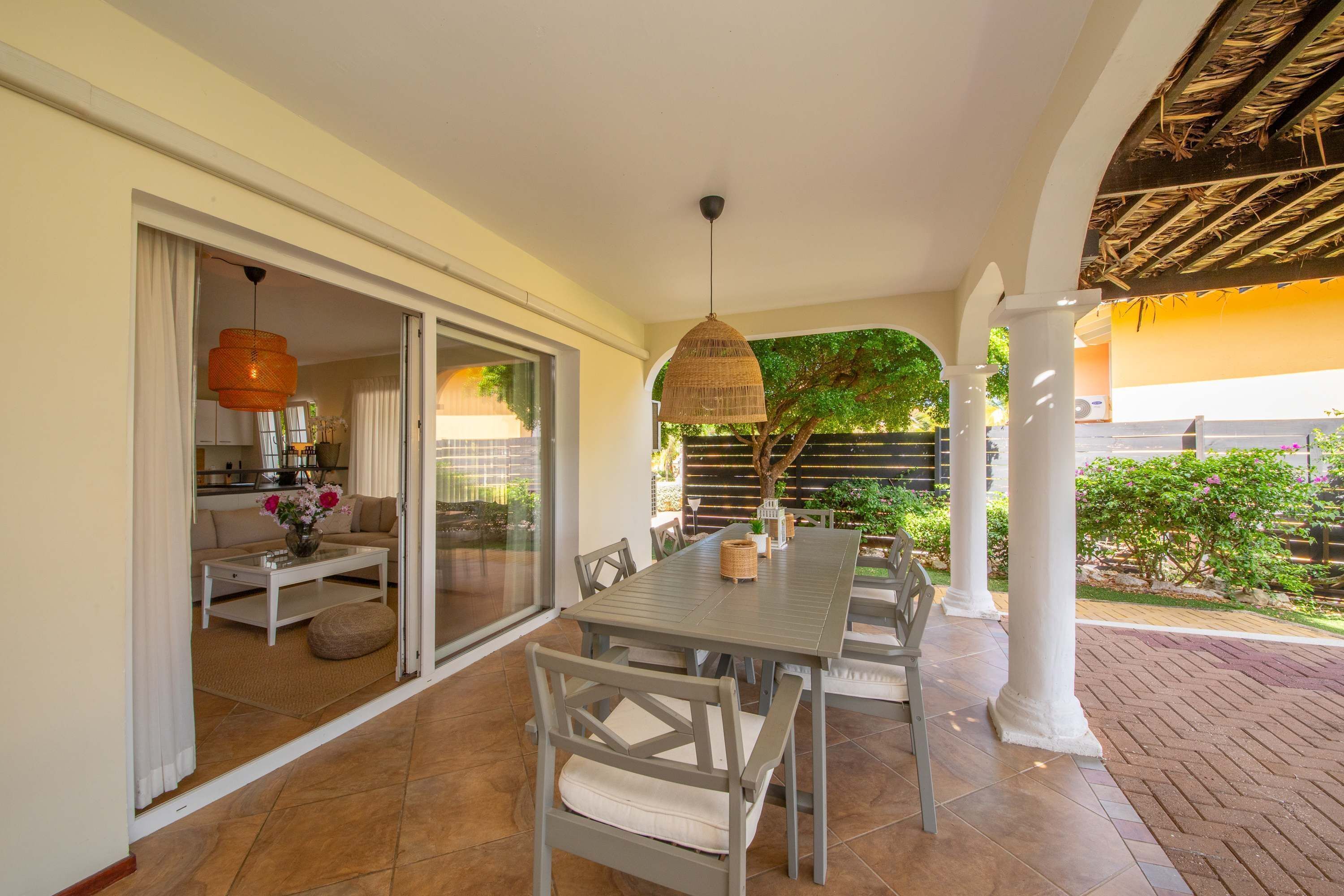 A dining area with a table and chairs, a hanging light fixture, and a view of the outdoors.