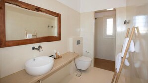 A bathroom with a large mirror, a sink, a toilet, and a towel rack. - Adyton Luxury Suite Mykonos Exclusive Pool Oasis (Mykonos)