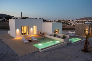 A modern villa with a swimming pool, outdoor seating, and a view of the surrounding landscape. - Adyton Luxury Suites Mykonos Private Pool Getaway (Mykonos)