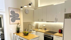 Une cuisine moderne avec des armoires blanches, un plan de travail en bois, un évier, une cuisinière et une horloge au mur.