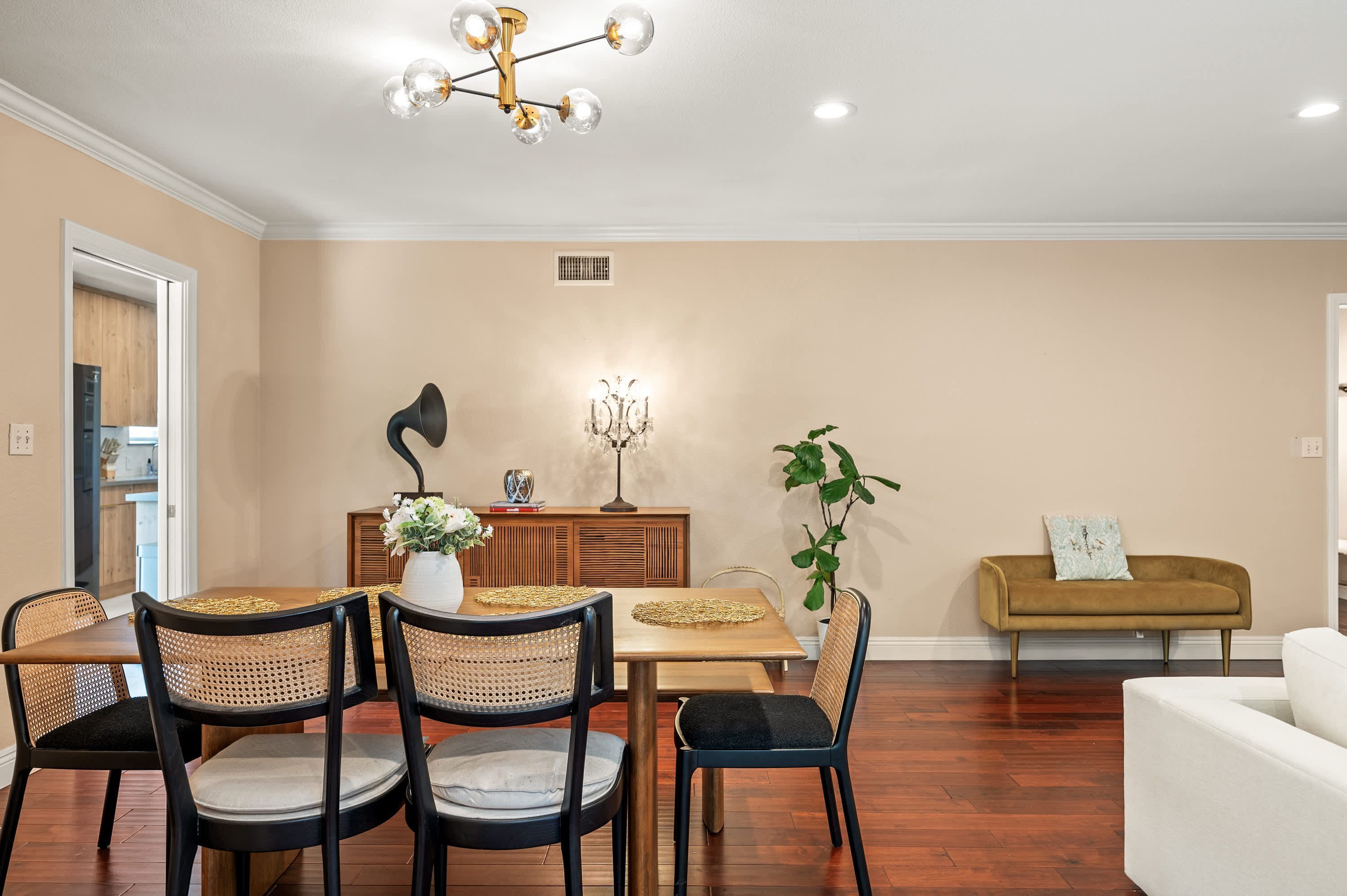 A dining area with a wooden table, black chairs, and a chandelier.