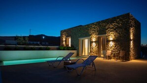 A stone building with a pool and lounge chairs. - Adyton Luxury Suites Mykonos Poolside Luxury (Mykonos)