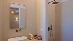 A modern bathroom with a large oval sink, a mirror, and a shower. - Adyton Luxury Suites Mykonos Poolside Luxury (Mykonos)