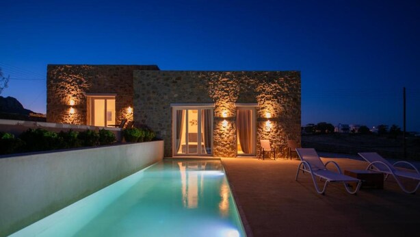 A modern building with a swimming pool, stone walls, and outdoor seating. - Adyton Luxury Suites Mykonos Poolside Luxury (Mykonos)