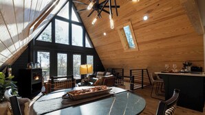 Un interior de madera acogedor con techos altos, chimenea, comedor y cocina.
