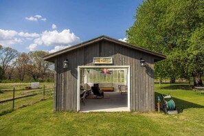 Un cobertizo de madera con un letrero que dice 'SHE SHED' y un patio cubierto con asientos.