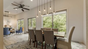 Un espace repas comprenant une grande table, des chaises et des lampes suspendues.