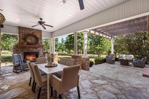 A covered patio with a stone fireplace, outdoor seating, and a ceiling fan. - The Highlands mansion, sleeps 28 (Decatur)