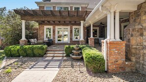 A brick house with a covered patio, stone pillars, and a stone chimney. - The Highlands mansion, sleeps 28 (Decatur)