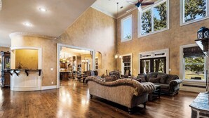 A spacious living room with hardwood floors, a large sofa, and a fireplace. - The Highlands mansion, sleeps 28 (Decatur)