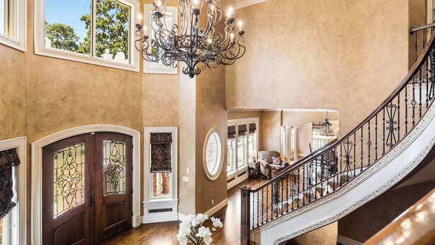 A grand foyer with a wooden staircase, a chandelier, and a vase with flowers. - The Highlands mansion, sleeps 28 (Decatur)