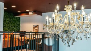 A modern interior with a chandelier, a green wall, and a bed with a patterned rug. - The Loft on Campus Su (Fayetteville)