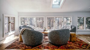 Un salon spacieux doté de grandes fenêtres, d’un puits de lumière et d’un coin salon confortable agrémenté d’un tapis à motifs.