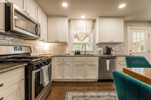 A kitchen with white cabinets, a stainless steel stove, a microwave, and a dishwasher. - Porch on 3rd, Bentonville, bikable to DT and Coler (Bentonville)
