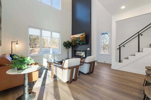 A spacious living area with a fireplace, a dining table, and a staircase. - Sapphire Lodge at Bella Vista (Bella Vista)