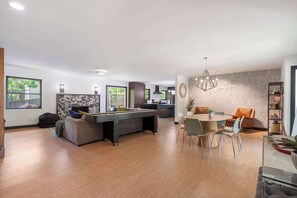 A modern living room with a pool table, dining area, and a kitchen in the background. - The Woolsey Summary: (Fayetteville)