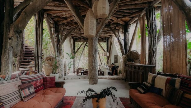 A rustic interior with wooden beams, a central seating area with sofas, a coffee table, and a hanging light fixture. - Rooftop Pool + Gym + Laundry + Coworking + Cinema (Tulum)