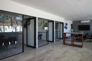 An office space with glass partitions, a wooden table, and office chairs. - Tulum Condo w/ Rooftop, Pool, Gym, Cowork, Cinema (Tulum)