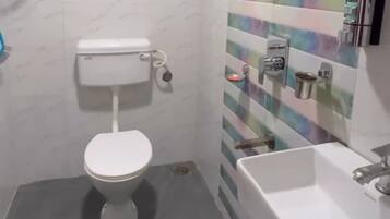 A bathroom with a toilet, a shower, and a sink.
