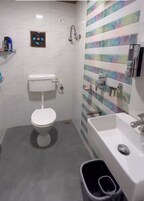 A bathroom with a toilet, a shower, and a sink.