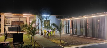Un espacio exterior moderno con zona de estar, una piscina pequeña y una sección cubierta con puertas de vidrio.