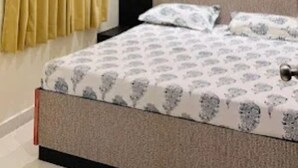 A bedroom with a bed, a ceiling fan, an air conditioning unit, curtains, and a wall decoration.