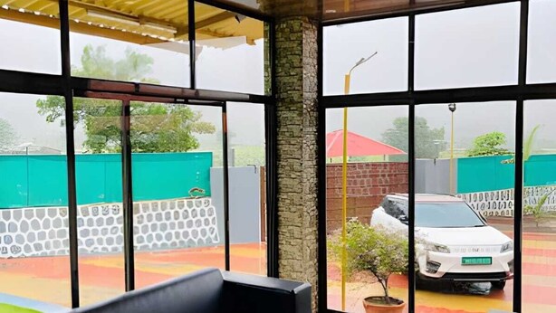 A modern indoor seating area with large windows, a ceiling fan, and a view of the outside.