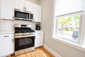 A kitchen with white cabinets, a stainless steel stove, a microwave, and an oven. - Jennifer's Spa-Like Apt King Bed Historic Broadway (Providence)