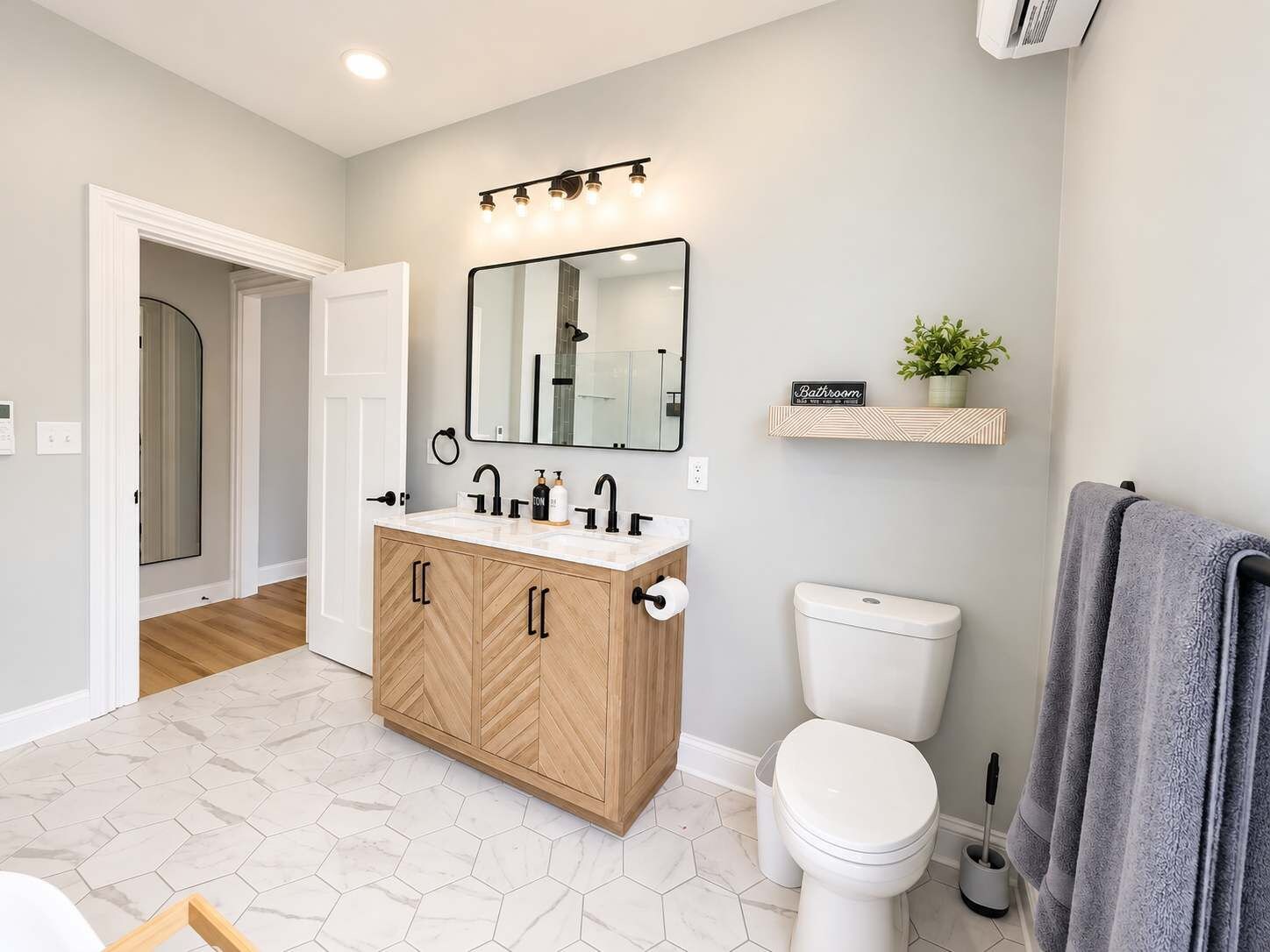 Un baño moderno con tocador de madera, inodoro y zona de ducha.