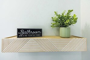 A bathroom sign with a potted plant. - Jennifer's Spa-Like Apt King Bed Historic Broadway (Providence)