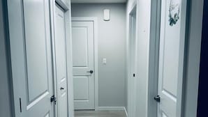 Um corredor com portas brancas, piso de madeira claro e iluminação embutida no teto.