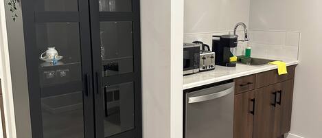 A modern kitchen with a black cabinet, a dishwasher, and a microwave.