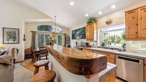 Une cuisine moderne dotée d’un îlot central, de meubles en bois et d’une grande fenêtre qui laisse entrer la lumière naturelle.