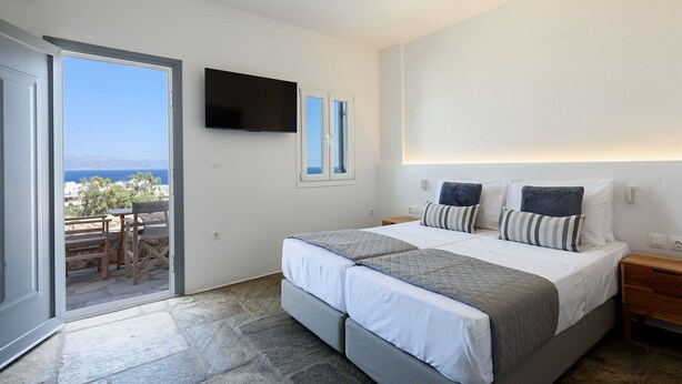 Ein Schlafzimmer mit Bett, Fernseher, Nachttisch und Meerblick.