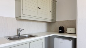 Eine kleine Küche mit Spüle, Kaffeemaschine, Toaster und Kühlschrank.